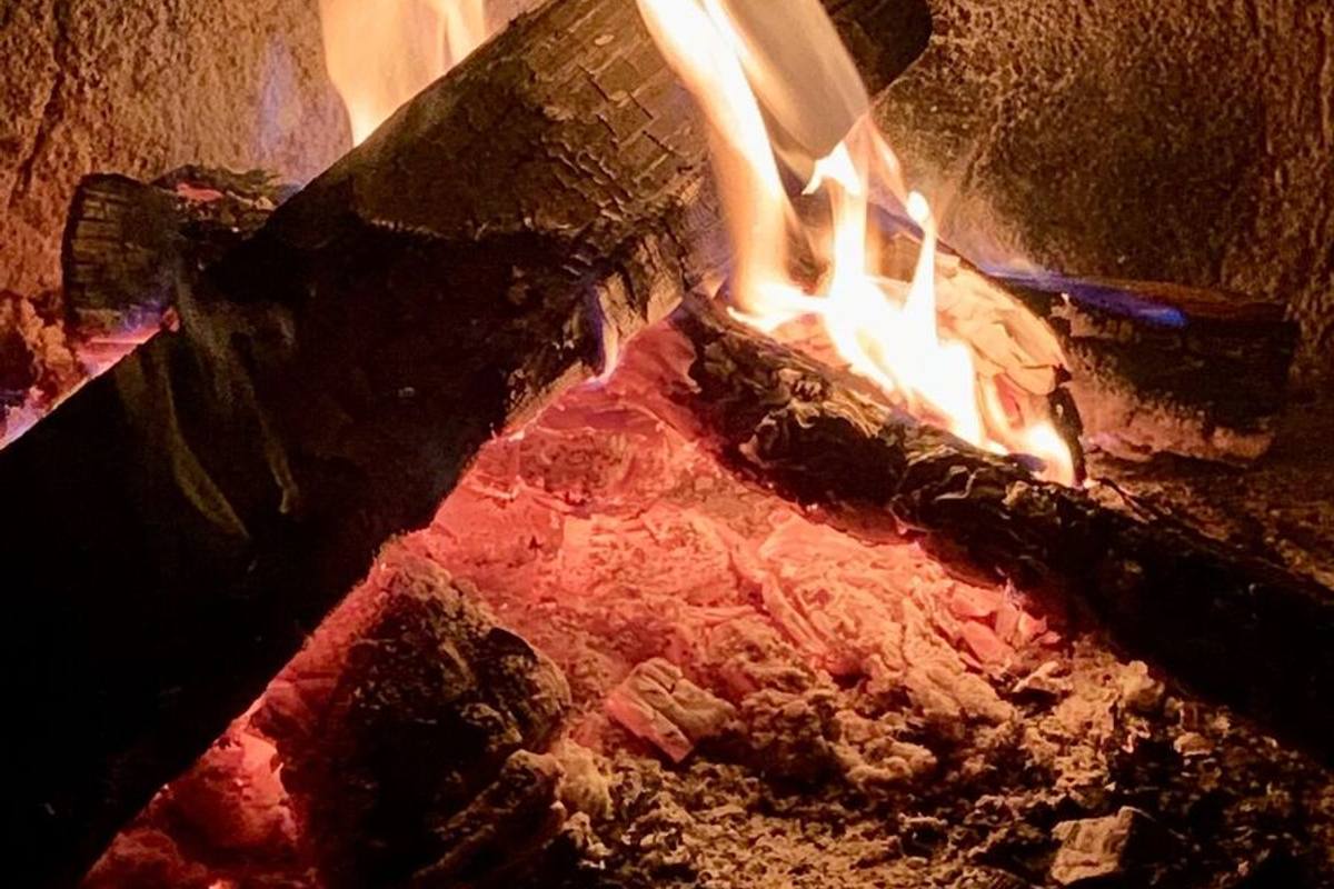 Split logs burning down to coals inside the firebox of an offset smoker.