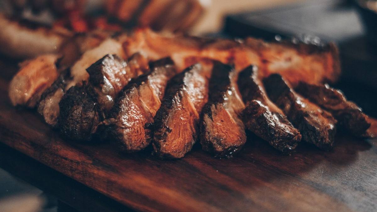 A smoked beef cut carved into thick slices, dark bark on every edge.